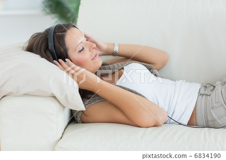 Smiling woman lying on the sofa and listening music 6834190