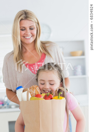Daughter looking into grocery bag with mother watching 6834924