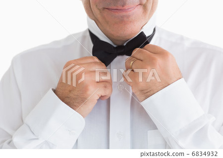 Smiling man fixing bow tie Smiling man fixing bow tie 6834932