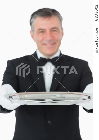 Waiter looking at the camera while holding a silver tray Waiter looking at the camera while holding a silver tray 6835002