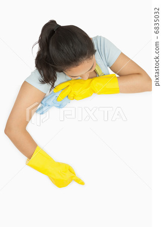 Woman in rubber gloves pointing on white surface 6835032