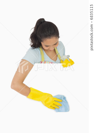 Smiling woman in gloves cleaning white surface 6835115