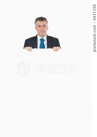 Smiling businessman looking over top of board Smiling businessman looking over top of board 6835198