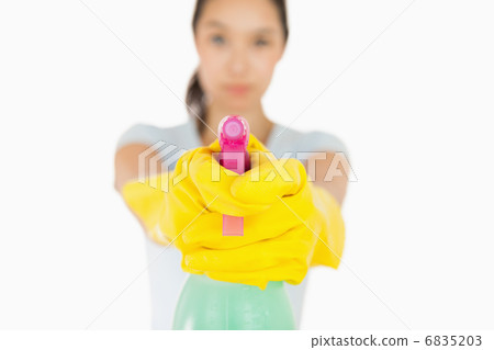 Serious woman pointing a spray bottle at the camera Serious woman pointing a spray bottle at the camera 6835203