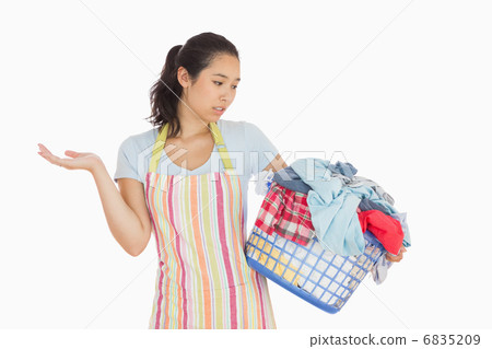 Quizzical looking young woman looking at basket 6835209