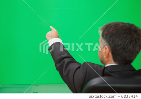 Businessman pointing on a green wall 6835414