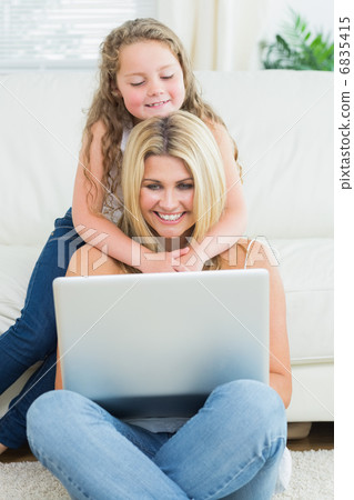 Mother using notebook while sitting on the floor 6835415