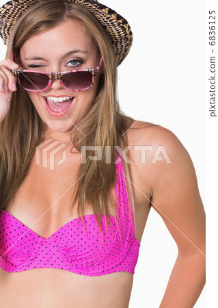 Woman holding her glasses while winking 6836125