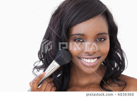 Smiling woman using makeup brush Smiling woman using makeup brush 6836368