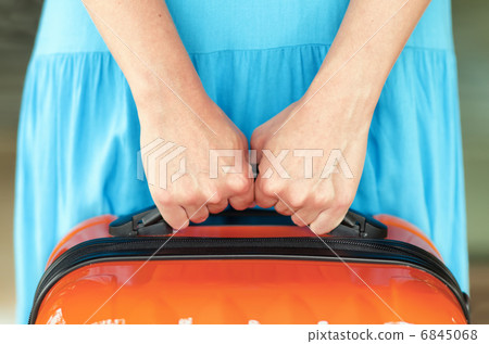 Woman in blue dress holds orange suitcase in hands Woman in blue dress holds orange suitcase in hands 6845068