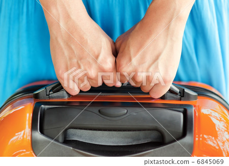 Woman in blue dress holds orange suitcase in hands Woman in blue dress holds orange suitcase in hands 6845069