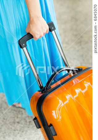 Woman in blue dress holds orange suitcase in hand Woman in blue dress holds orange suitcase in hand 6845070