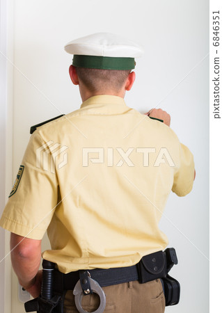 Police officer knocking on front door of home 6846351