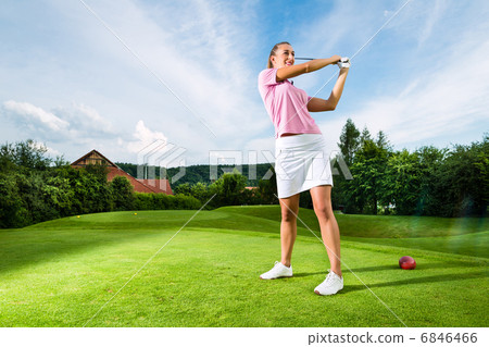 Young female golf player on course doing golf swing Young female golf player on course doing golf swing 6846466