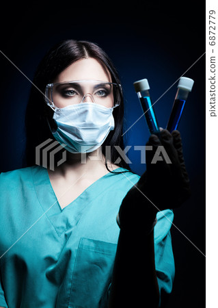 scientist looking at tubes with blue liquid in dark 6872779