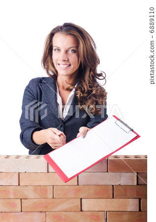 Woman builder and brick wall 6889110