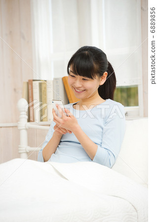 A woman who enjoys smartphone in bed A woman who enjoys smartphone in bed 6889856