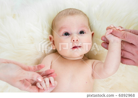 baby girl holding parental hands lying on fur bed baby girl holding parental hands lying on fur bed 6892968