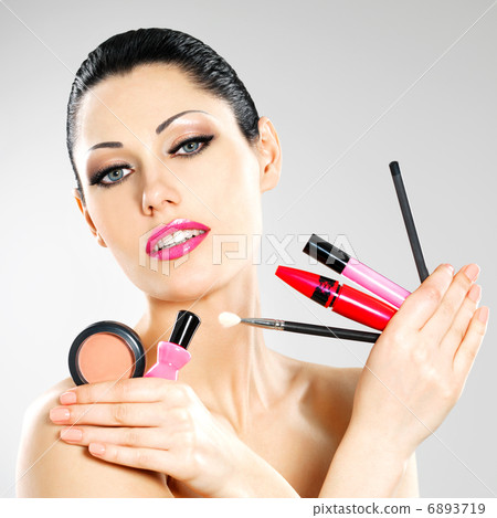 Woman with makeup cosmetic tools near her face. Woman with makeup cosmetic tools near her face. 6893719