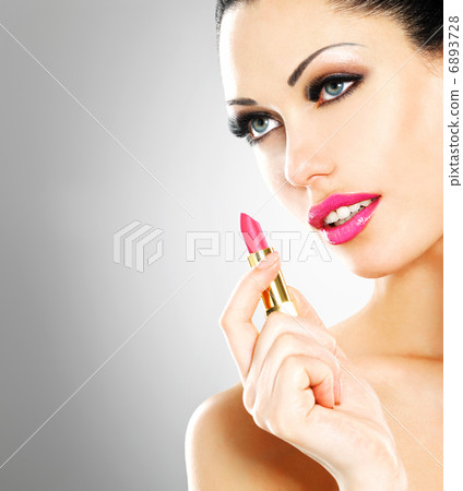 Beautiful woman applying pink lipstick on lips 6893728