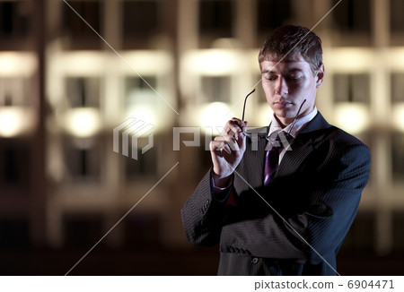 Handsome businessman and light building at night city in the bac Handsome businessman and light building at night city in the bac 6904471