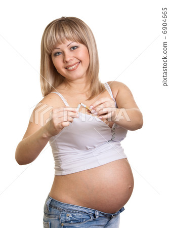 Young pregnant woman holding a broken cigarette while standing a Young pregnant woman holding a broken cigarette while standing a 6904665
