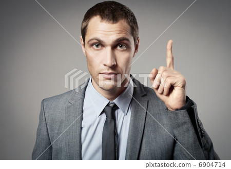 Young businessman criticizing on gray background Young businessman criticizing on gray background 6904714