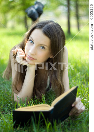 Young student reading book on meadow Young student reading book on meadow 6905336