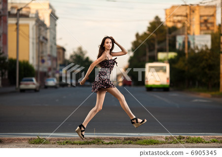 young carefree woman jumping at the street in city 6905345