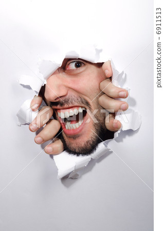 Male face through the hole in paper Male face through the hole in paper 6911513