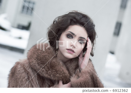 Femininity. Portrait of Sophisticated Young Brunette in Brown Fur Coat Outdoors Femininity. Portrait of Sophisticated Young Brunette in Brown Fur Coat Outdoors 6912362