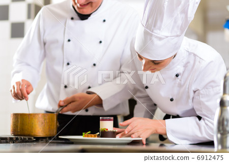 Chef team in restaurant kitchen with dessert 6912475