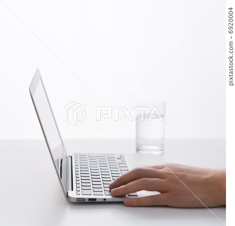 雙手在筆記型電腦上打字,旁邊放著一杯水。 雙手在筆記型電腦上打字,旁邊放著一杯水。 6920004