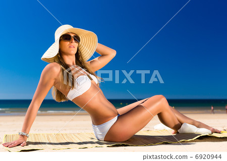 Attractive woman sitting in the sun on beach Attractive woman sitting in the sun on beach 6920944