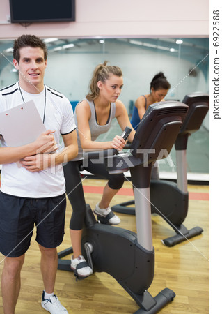 Instructor at spinning class with two women Instructor at spinning class with two women 6922588