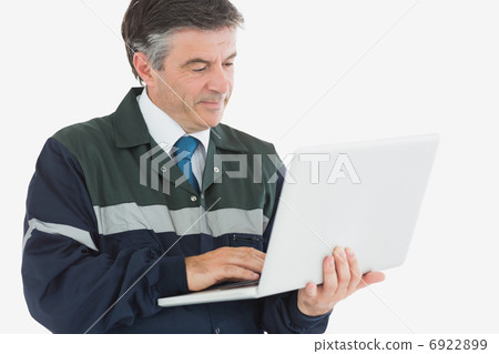Repairman in coveralls using laptop 6922899