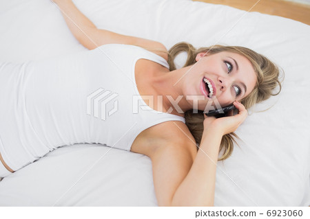 Calm woman phoning lying on the bed Calm woman phoning lying on the bed 6923060
