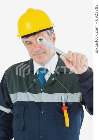 Mature repairman looking through wrench 6923288
