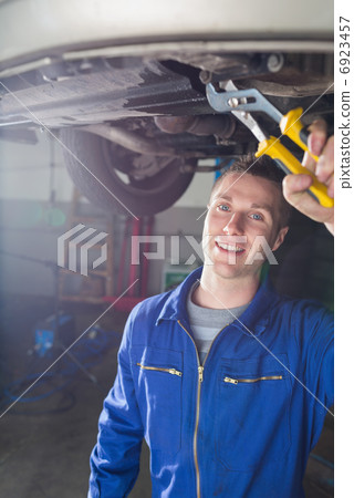 Happy male mechanic repairing car Happy male mechanic repairing car 6923457