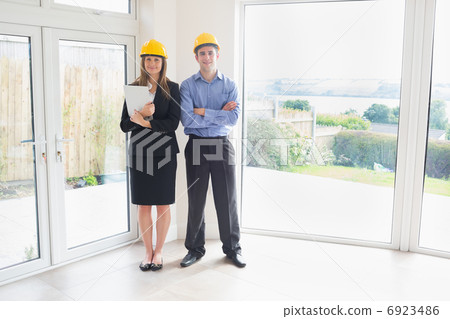 Estate agent and client wearing hardhats Estate agent and client wearing hardhats 6923486