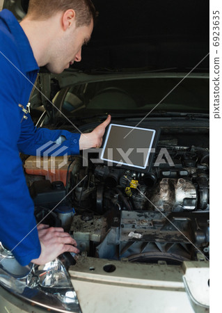 Mechanic by car holding tablet pc 6923635