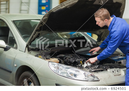 Mechanic with laptop checking engine 6924501