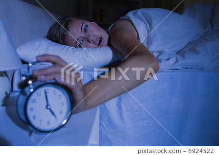 Awakening woman stopping her alarm clock 6924522