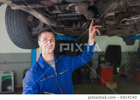 Male repairman examining under car 6924540
