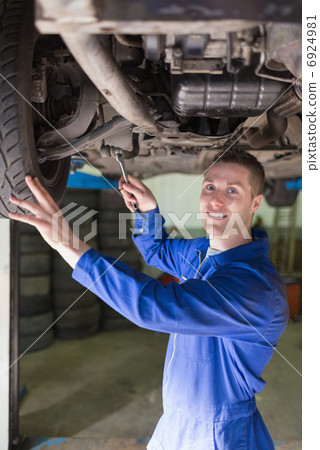 Mechanic in coveralls working under car 6924981