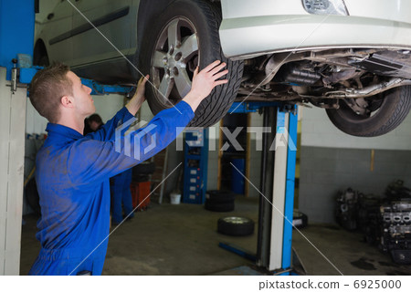 Auto mechanic examining car tire 6925000