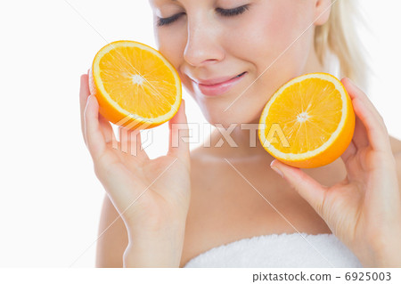 Woman with eyes closed holding slices of orange 6925003