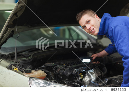 Confident repairman examining car engine Confident repairman examining car engine 6925133