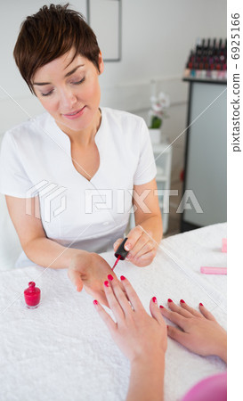 Woman applying nail varnish to finger nails 6925166