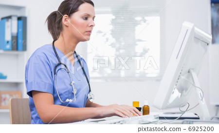 Female surgeon using computer at clinic 6925200